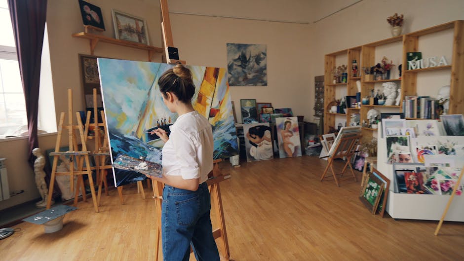 A dedicated artist working on a colorful canvas in a bright, organized studio.